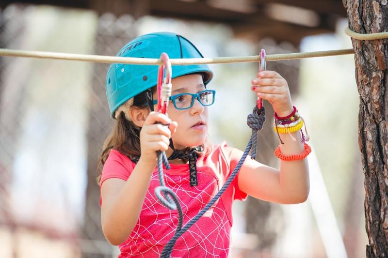 Una niña haciendo tirolina en campamentos en ingles españa
