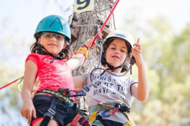 dos niñas jugando en un arbol en un campamento multiaventura