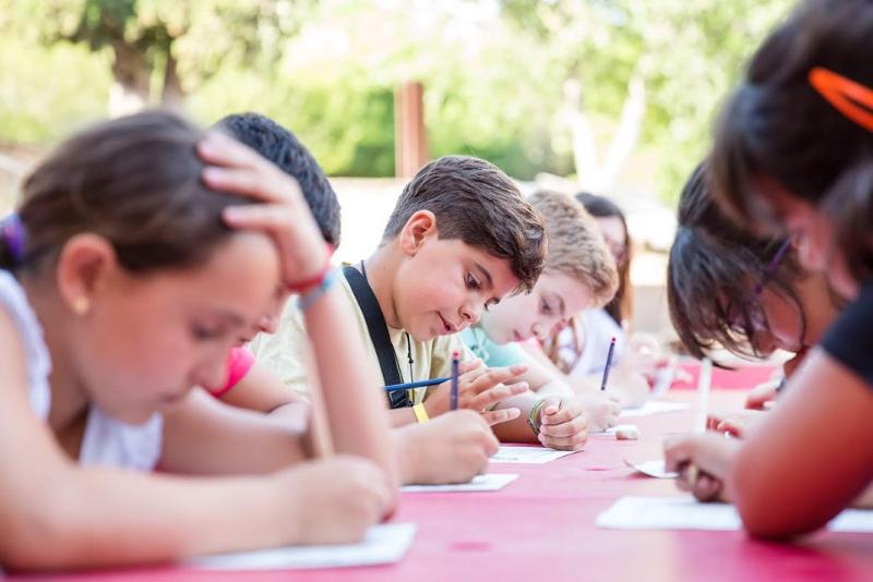 un grupo de niños anotando algo en una clase de un campamento de verano barcelona 