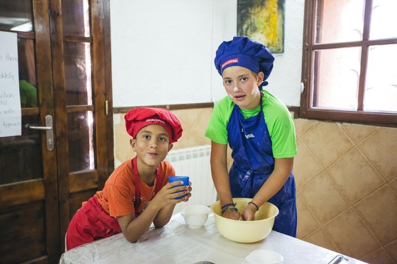 Dos niños amasando una masa en clase de cocina en un  campamento de cocina