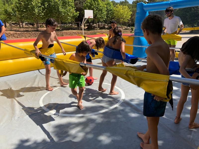 Un grupo de niños jugando en un castillo hinchable en un campamento de verano en barcelona 