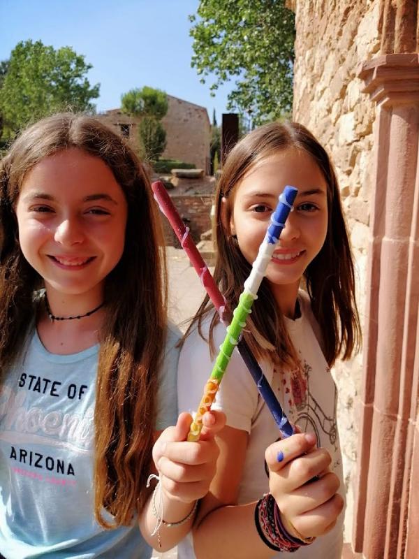 dos niñas mirando a camara sonriendo sujetando dos palos de colores en un  campamento de verano en barcelona 