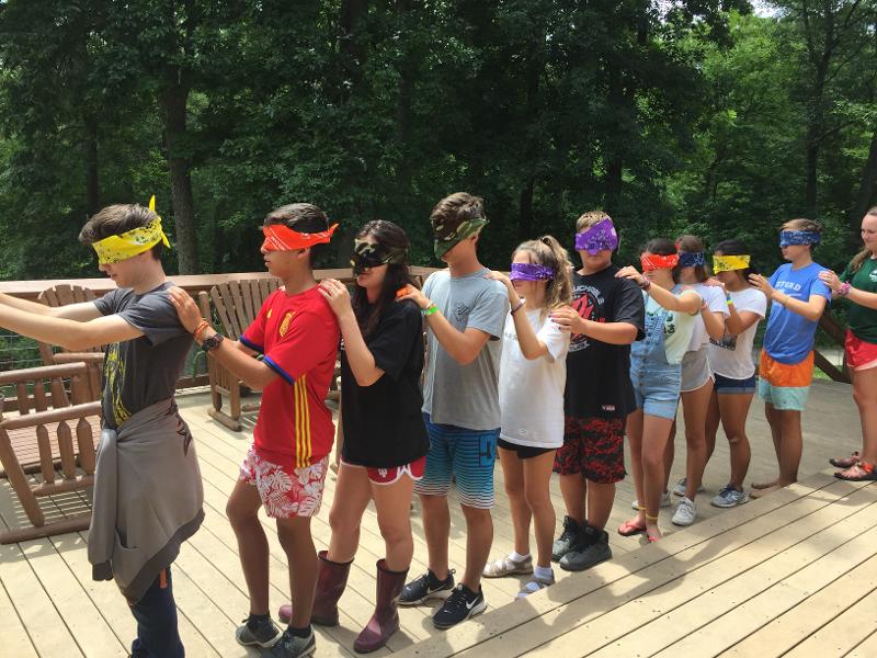 Grupo de niños sentados jugando a juegos en el exterior de los campamentos de verano de 15-18 años