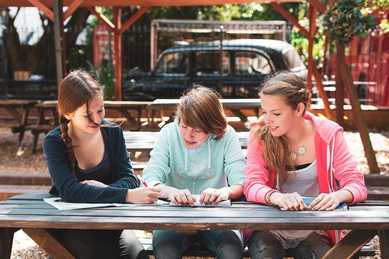Jóvenes sentadas al aire libre mientras estudian en el curso ingles en reino unido 