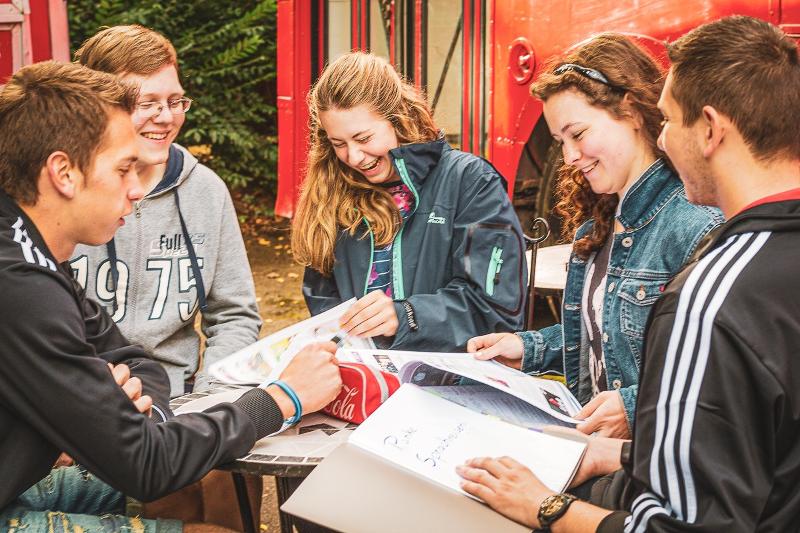 Grupo de niños de pie teniendo una conversación y preguntándose cosas durante un curso de ingles verano
