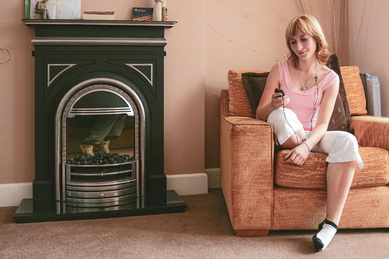 Jóven sentada en un sillón frente a la chimenea de su casa de acogida en el curso ingles en reino unido