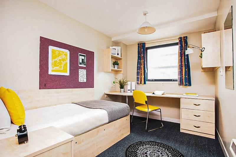 Habitación de residencia con cama, escritorio, silla y decoración moderna en el curso verano inglaterra