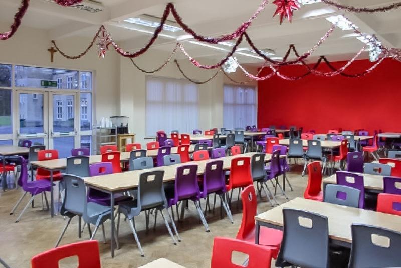 Comedor amplio con muchas mesas y sillas de colores y decoración de navidad en el curso de ingles inglaterra