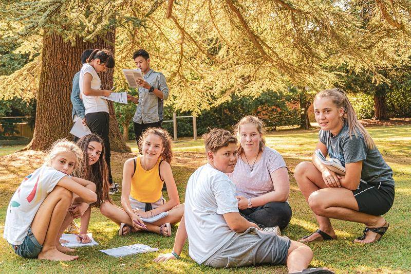 Grupo de jóvenes estudiando en el parque al aire libre en el curso ingles en reino unido 