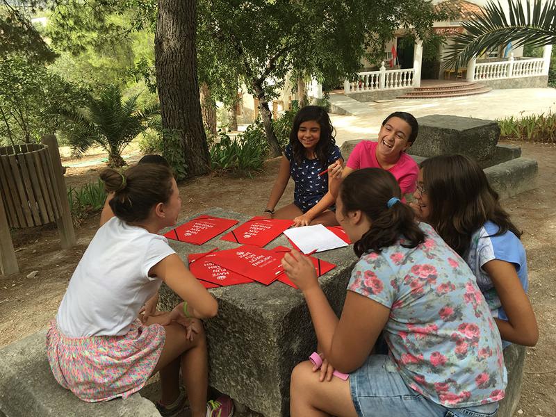 Niñas en taller de inglés riendo en un campamento de verano en USA.