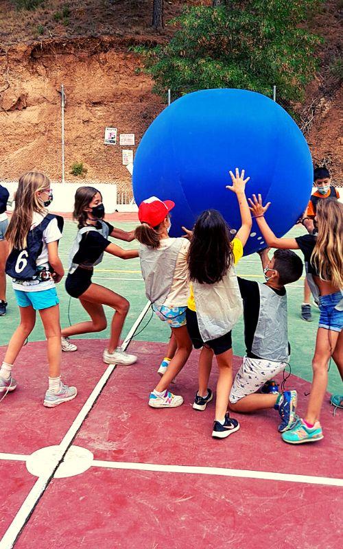 un grupo de niños jugando con una bola gigante en un campamento en cazorla
