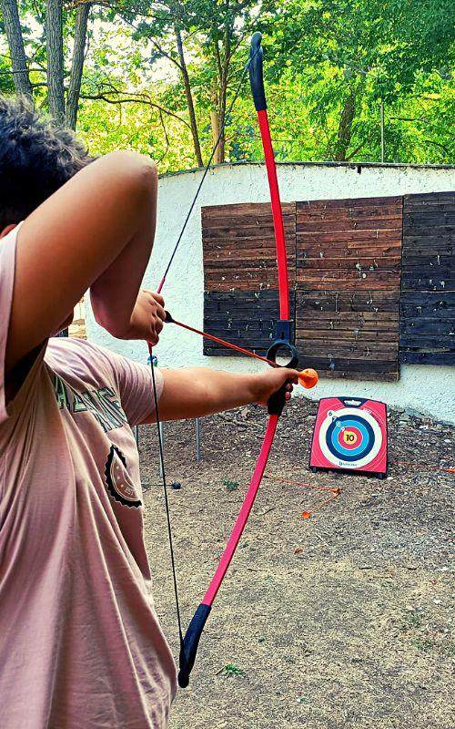 una niña jugando al tiro con arco en un campamento cazorla