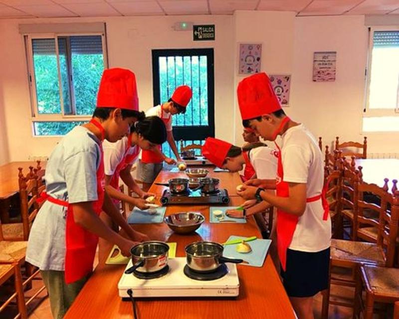 un grupo de niños cocinando en una clase de cocina en un campamento de verano jaen