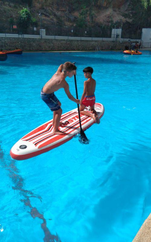dos niños practicando paddle surf en un campamento de verano jaen