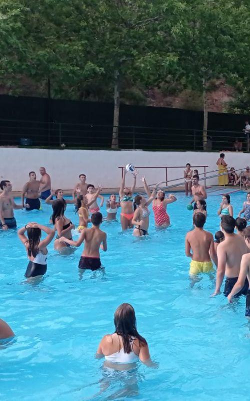 un grupo de niños en una piscina jugando con una pelota en un  campamento de verano jaen