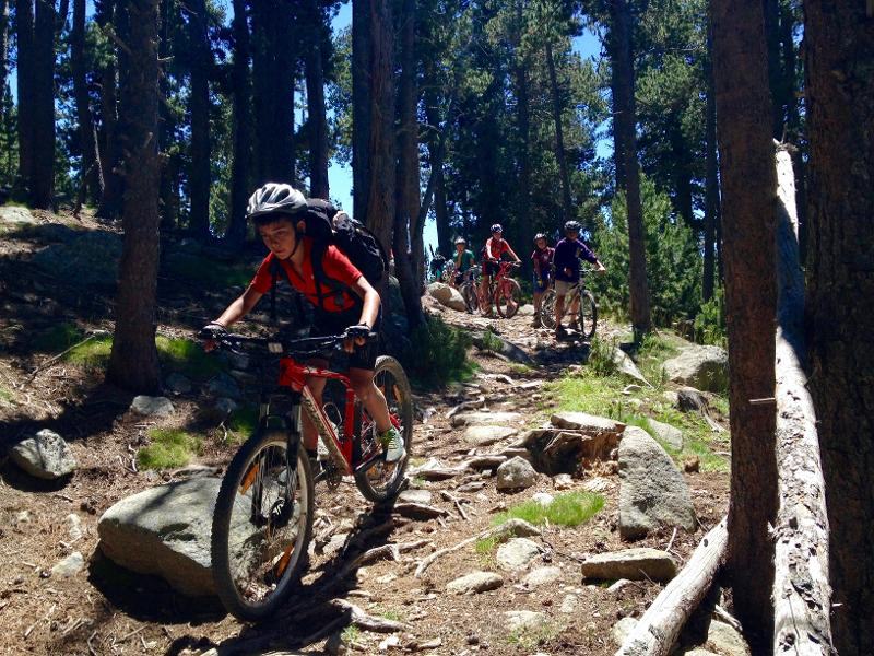 Un niño montando en bici en las montañas en un campamento multiaventura