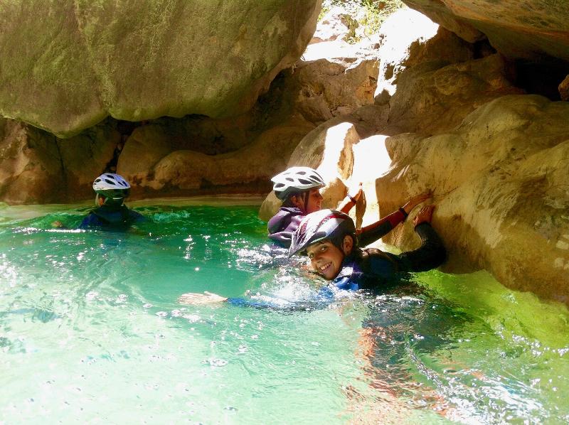Tres niños en un lago de las montañas en un campamento multiaventura