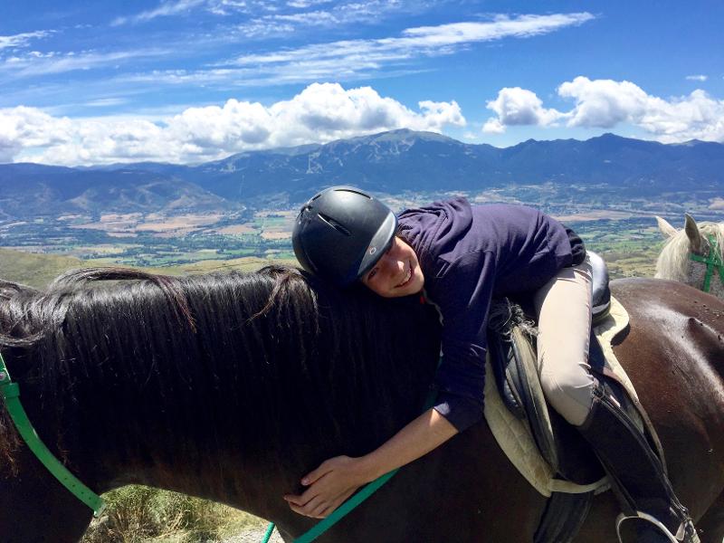 Una niña abrazando a un caballo en un campamento multiaventura