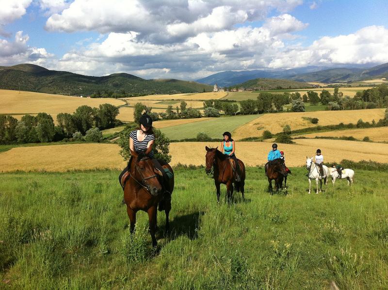 Un grupo de jovenes montando a caballo en las montañas en un viaje de verano para estudiantes