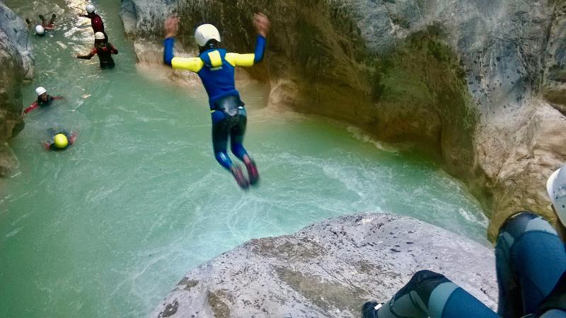 una niña saltando en un barranco en campamentos en pirineos