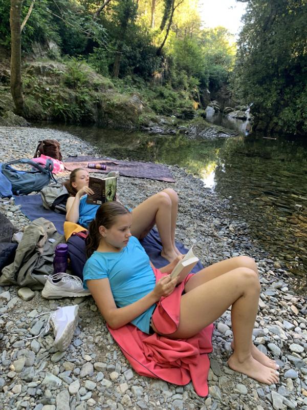 Chicas leyendo al lado del río en el campamento en irlanda