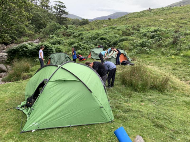Jóvenes montando sus tiendas de campaña en la naturaleza en el campamento de verano en irlanda