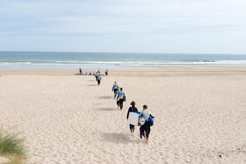 Jóvenes con sus tablas de surf de camino al agua en el campamento verano irlanda