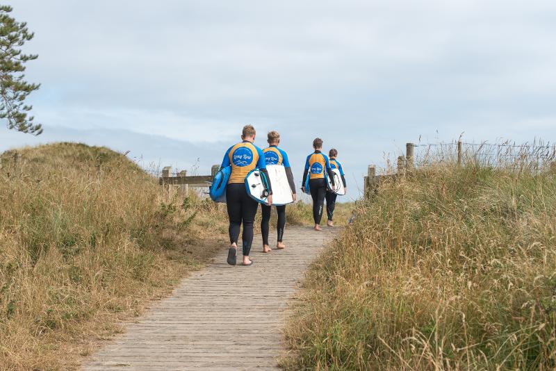 Jóvenes con neoprenos y tablas de surf en el campamento verano irlanda