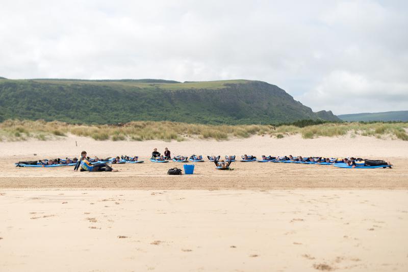 Grupo en el campamento de verano irlanda haciendo ejercicios en sus tablas de surf