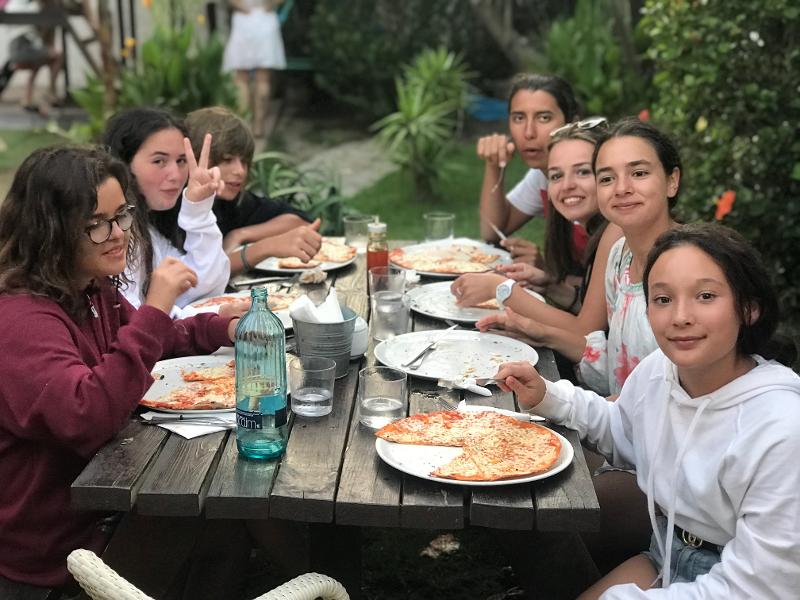 Una foto de un grupo de niños comiendo pizza en un campamento cadiz