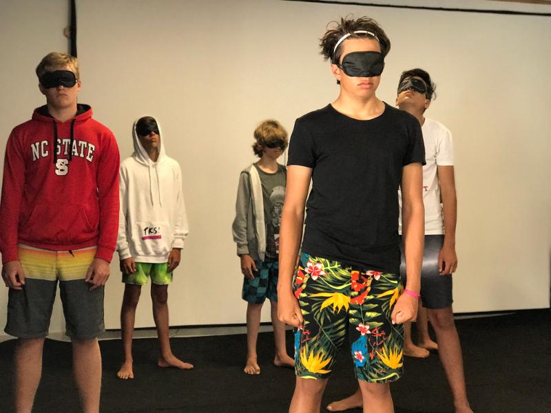 Un grupo de jovenes con antifaz en una clase extracurricular en un campamento kitesurf