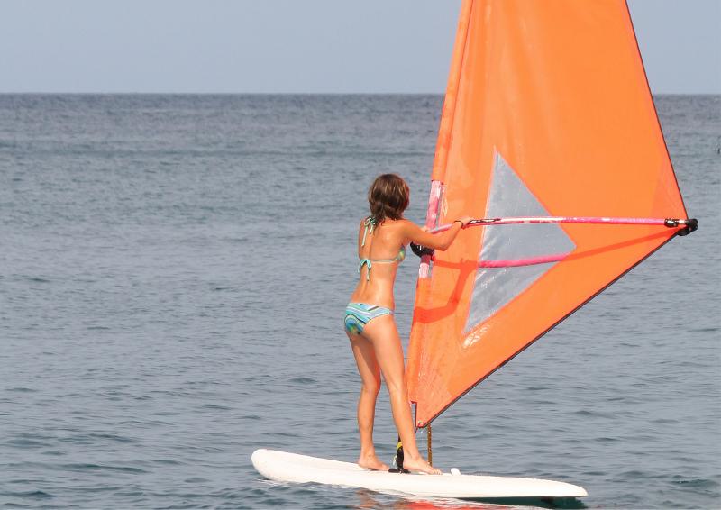 Una joven practicando windsurf en un campamento multideporte