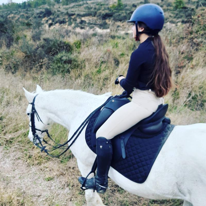 Una niña montando a caballo en un prado en un campamento de caballos