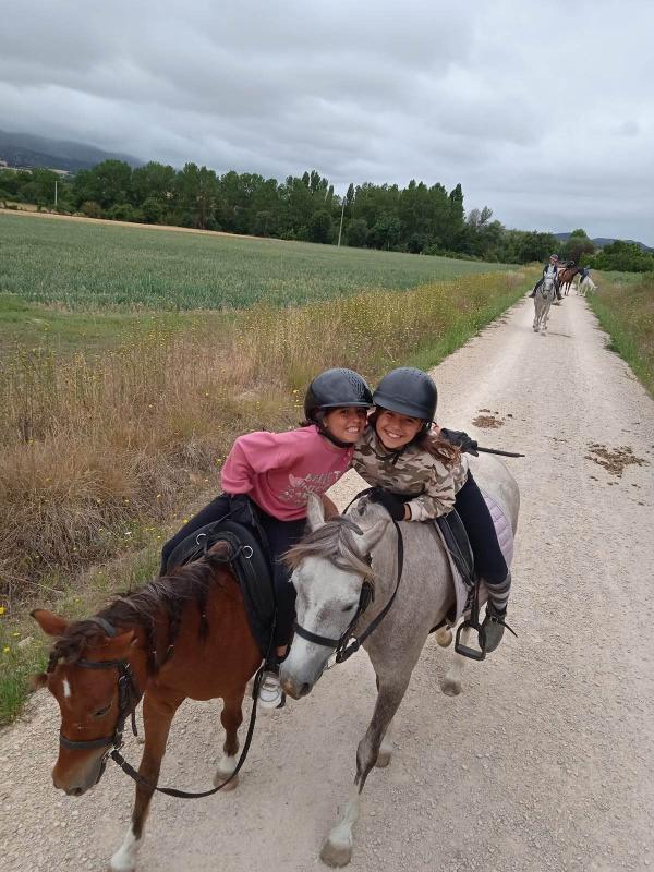 Dos niñas paseando con caballos en un campamento de caballos