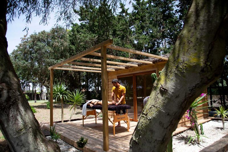 Monitor dando un masaje a un joven de un surf camp cadiz en una camilla en el jardín