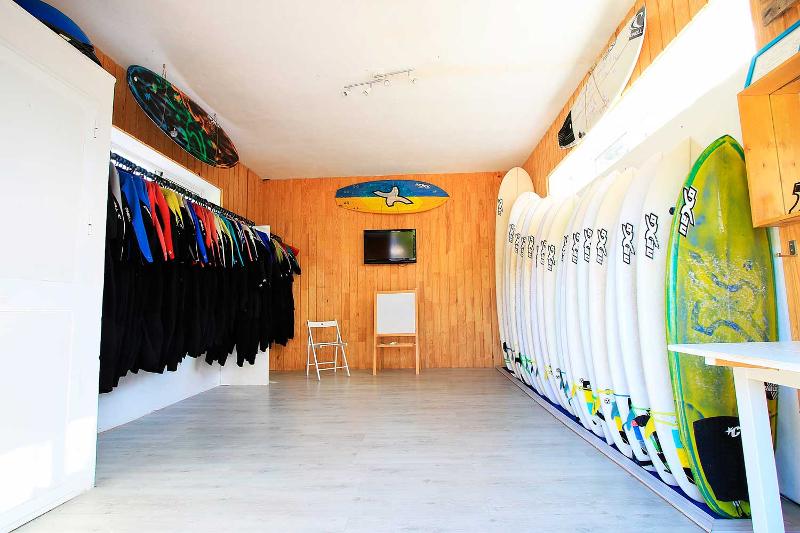Sala con neoprenos y tablas de surf en un surf camp cadiz 