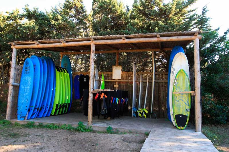 Tablas de surf y neoprenos guardados en una caseta al aire libre en un surf camp cadiz