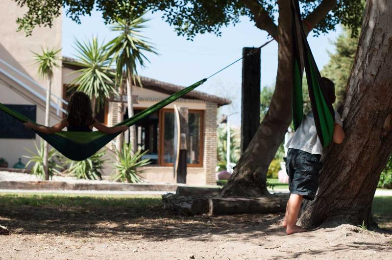 Niños usando unas hamacas atadas a un árbol en el jardín en un surf camp cadiz 