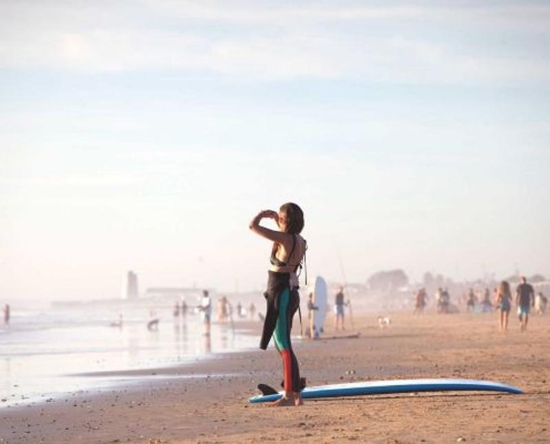 Uma jovem na praia com uma prancha de surf num curso de espanhol em Espanha