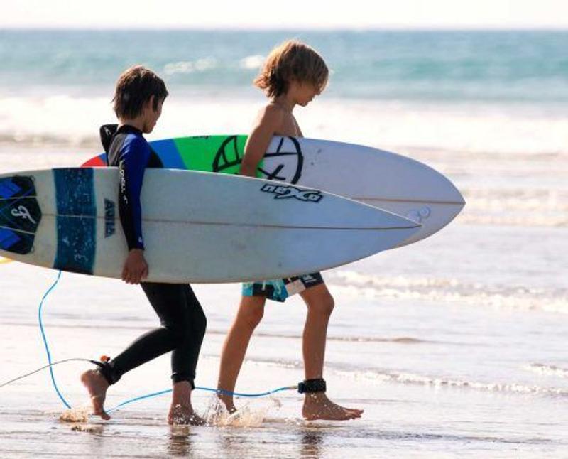 Niños entrando al mar antes de empezar a surfear en el Campamento de Surf en Cádiz