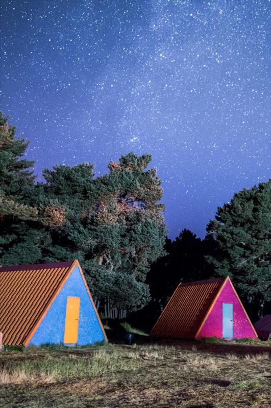 Una foto de unas cabañas de un campamento de musica en verano de noche