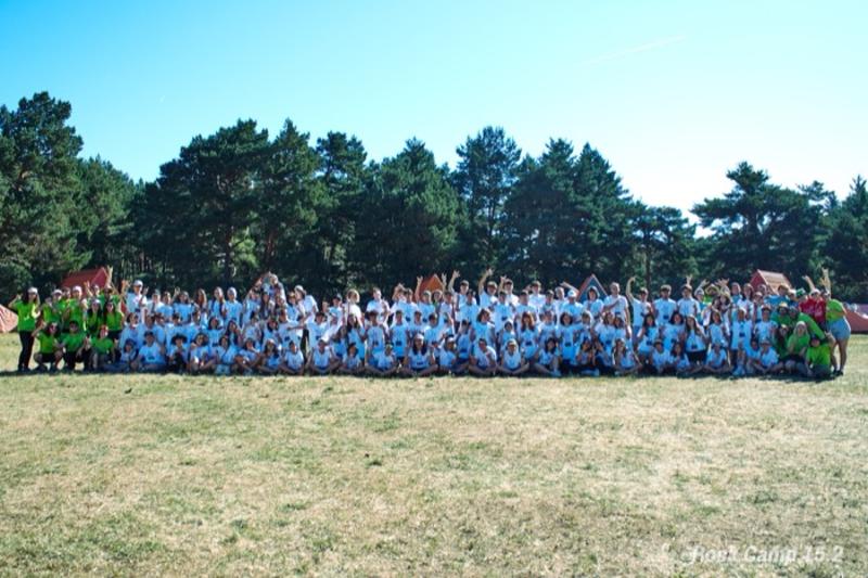 Un grupo grande de jóvenes reunidas en un parque en un campamento de verano musica