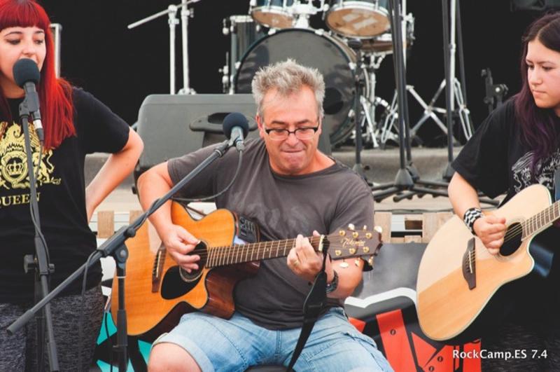 Un señor tocando al guitarra en un campamento de verano musica