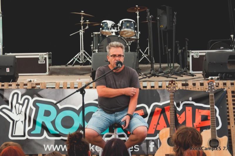 Un monitor con un micrófono hablando o cantando en un campamento de verano musica