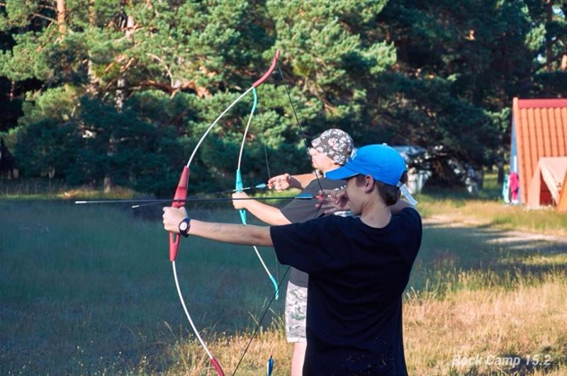 Un chico practicando el tiro con arco en un campamento de verano musica