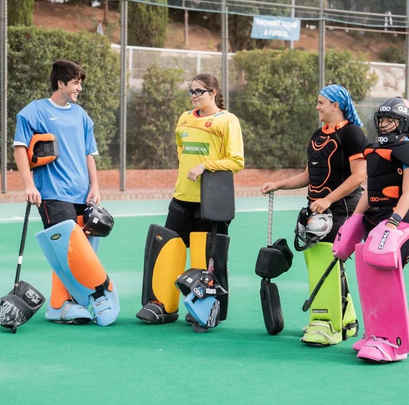 Grupo de participantes charlando mientras hacen actividades deportivas de hockey en las pistas del summer camp Valencia