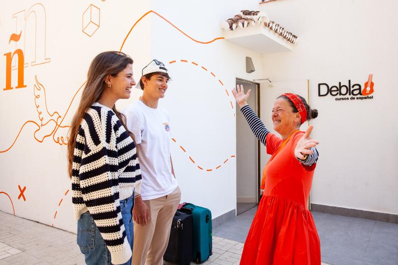 Mujer da la bienvenida a unos estudiantes sonriendo en el curso de español españa