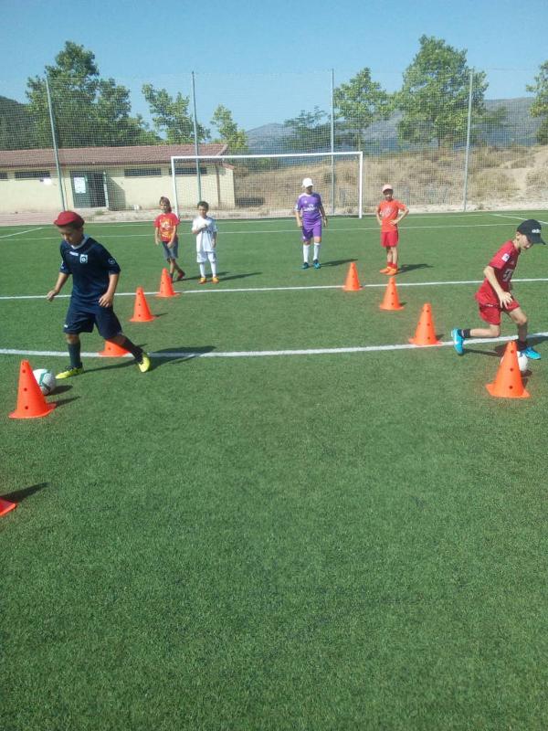 Un grupo de niños jugando al futbol en un campamento de futbol en madrid