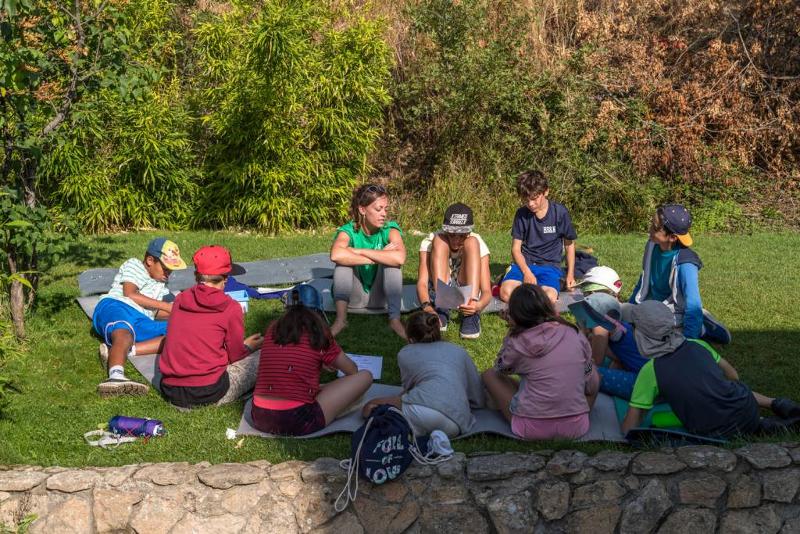 Un grupo de niños sentados en un jardín en un campamento de futbol en madrid