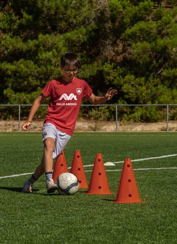 Un niño jugando al futbol en un campamento de futbol en madrid
